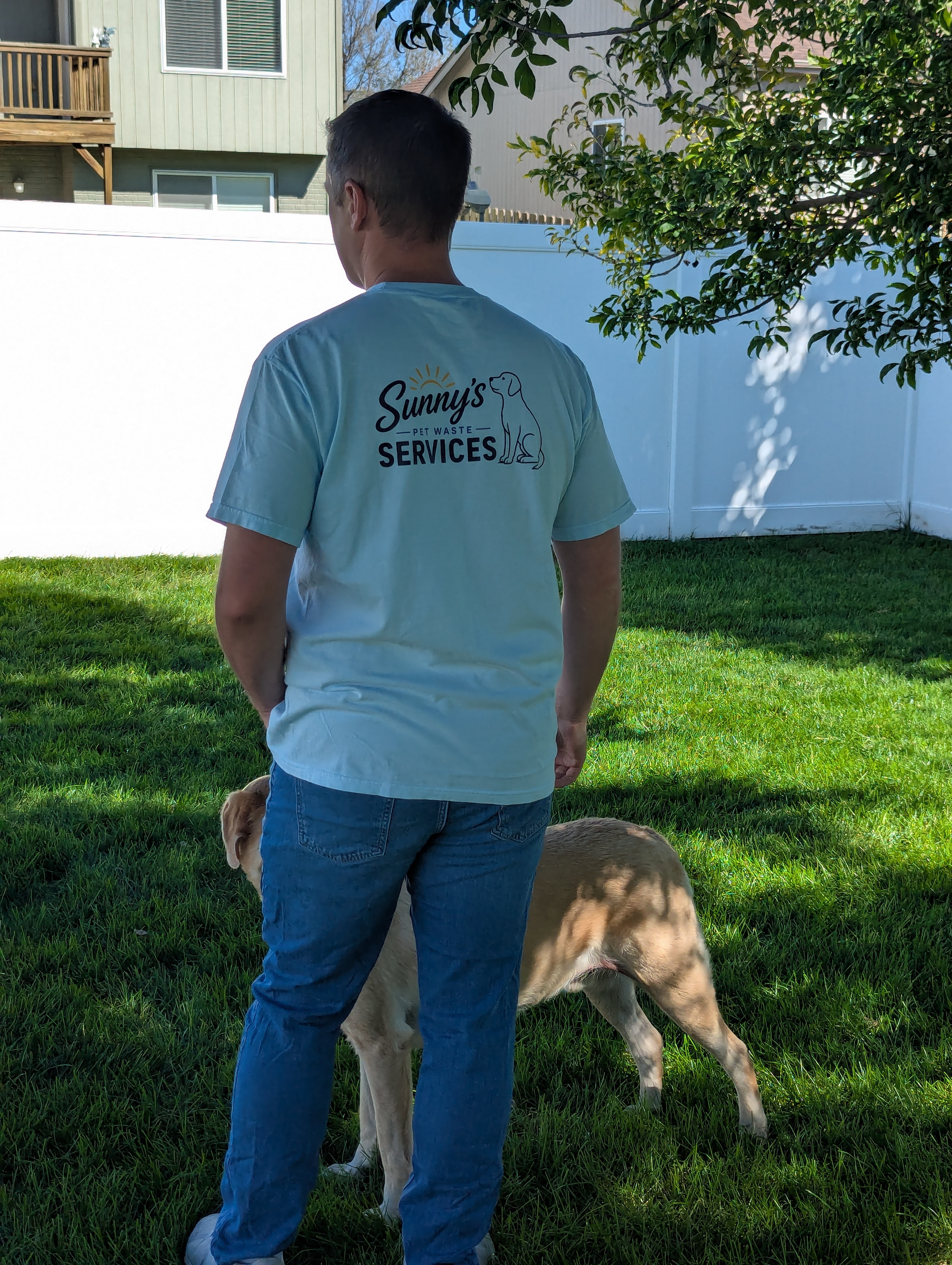 Sunny's Pet Waste Services team member in branded t-shirt with dog in a clean Omaha backyard