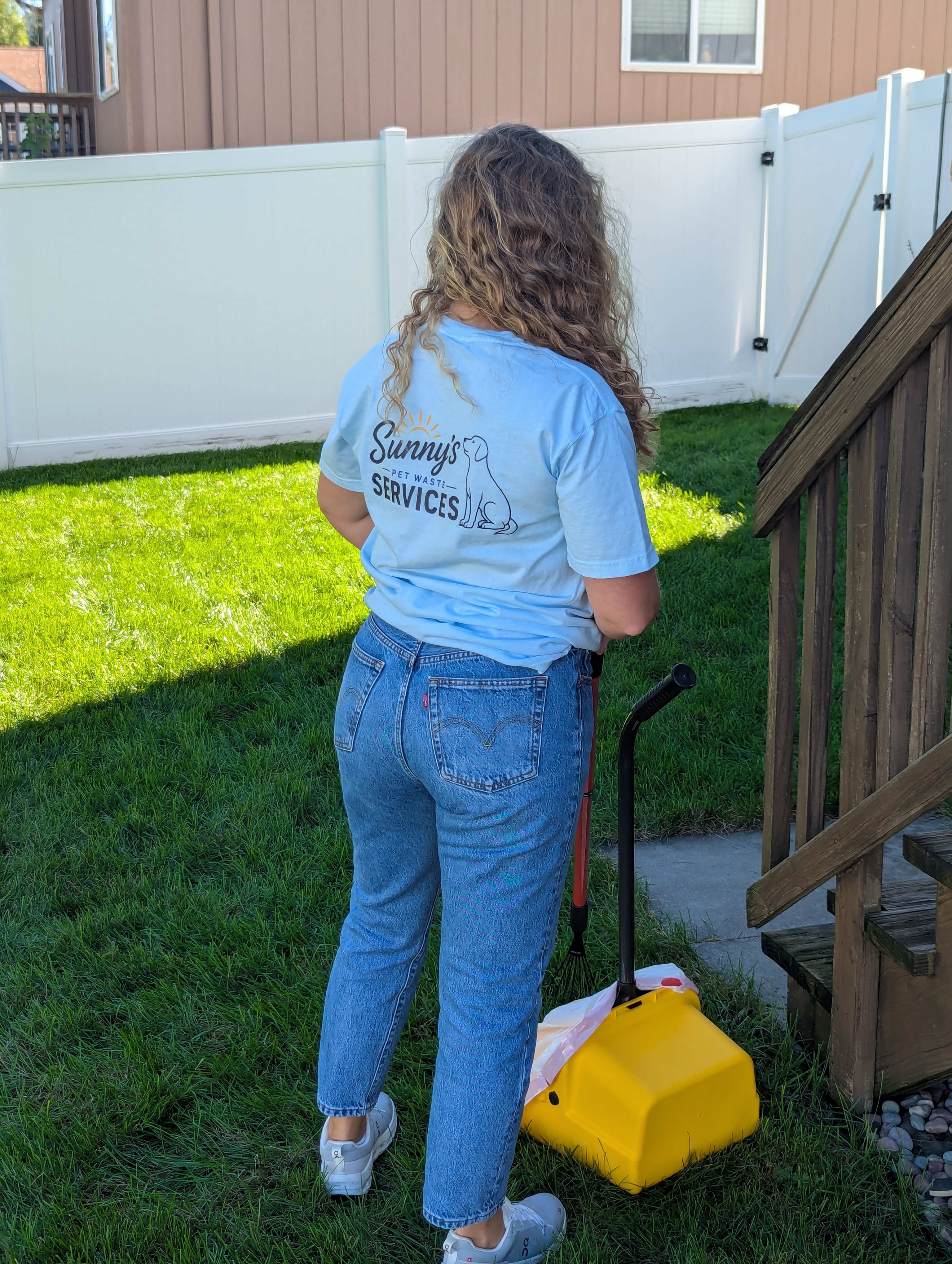 Sunny's Pet Waste Services team member in branded t-shirt with pet waste removal equipment in a clean Omaha backyard