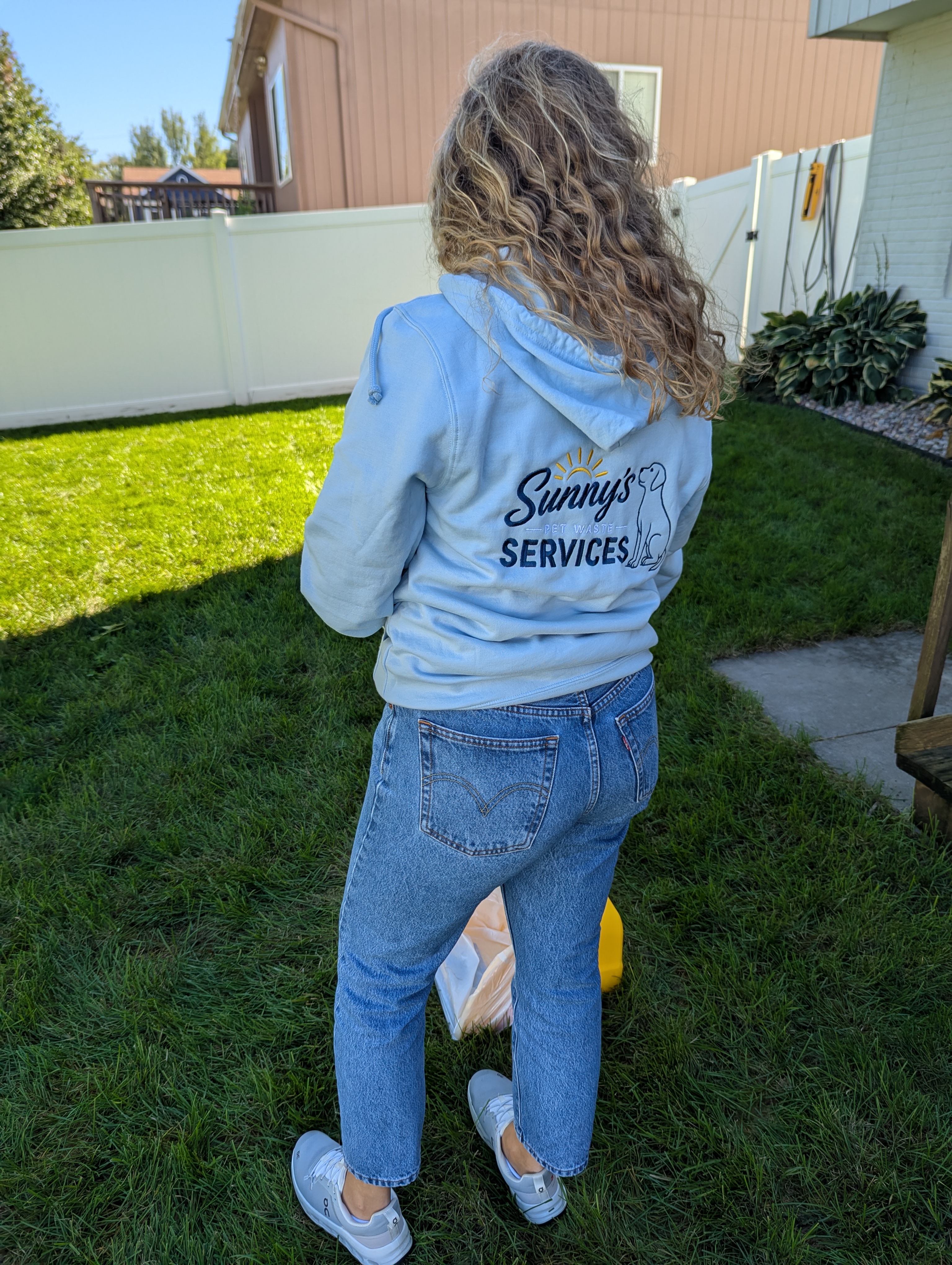 Sunny's Pet Waste Services team member in branded hoodie on a clean, well-maintained residential yard in Omaha