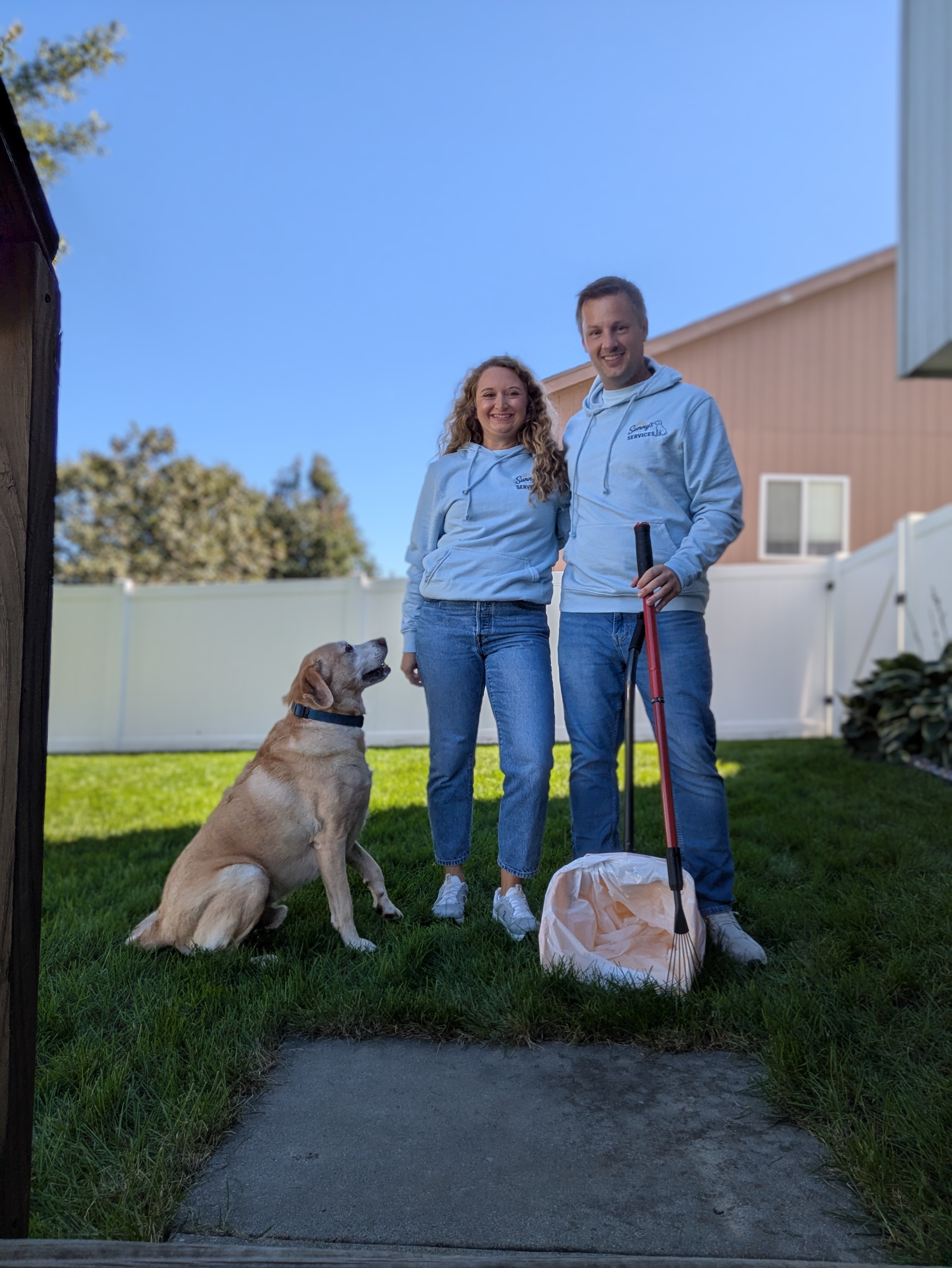 Sunny's Pet Waste Services team members with a dog and waste removal equipment in a clean Omaha backyard